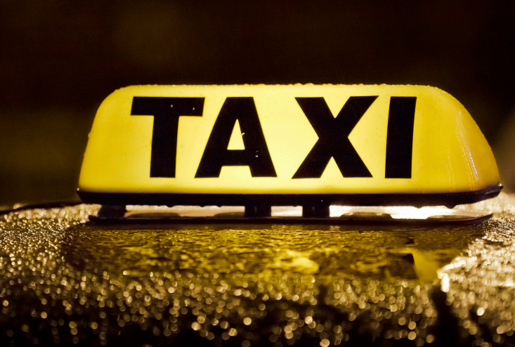 Yellow Taxi sign on top of a vehicle